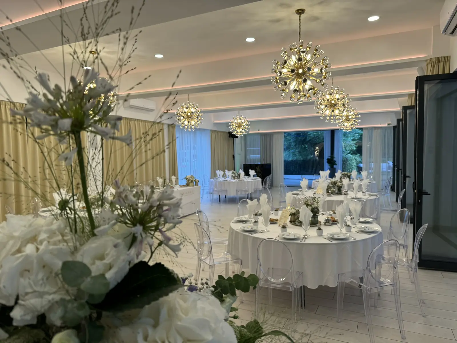 Elegáns fehér rendezvényterem terített asztalokkal